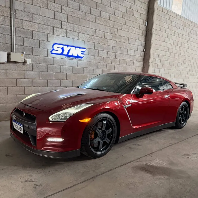 Red Nissan GT-R R35 in front of the illuminated Sync sign in the workshop