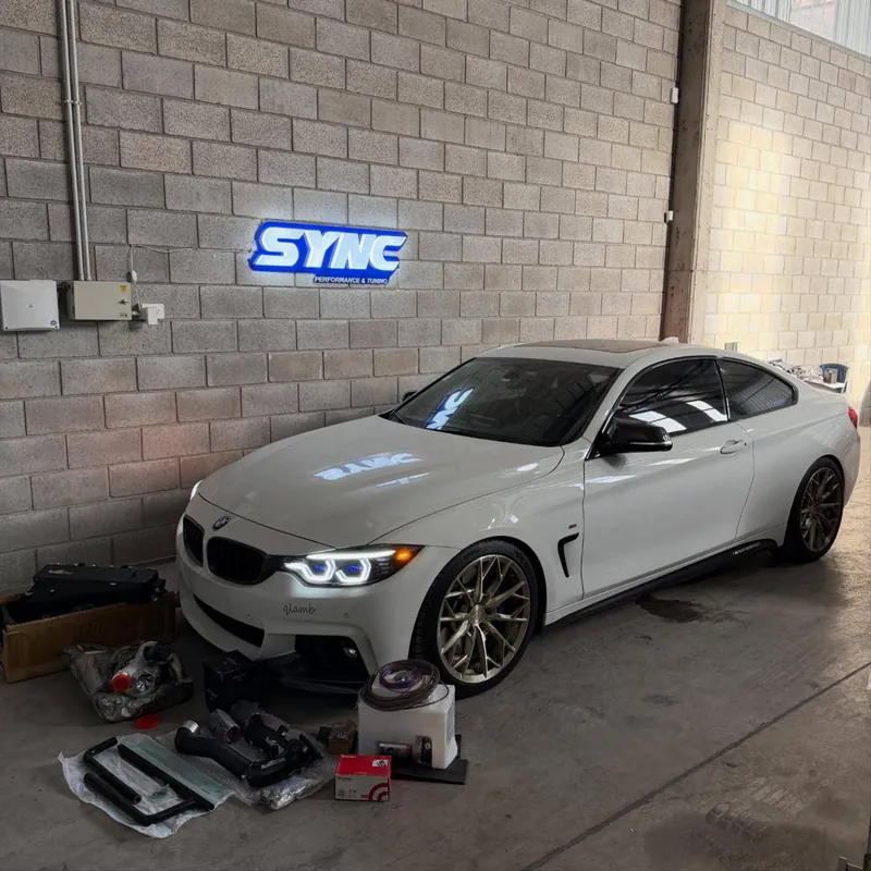 White BMW M440i in front of the Sync sign
